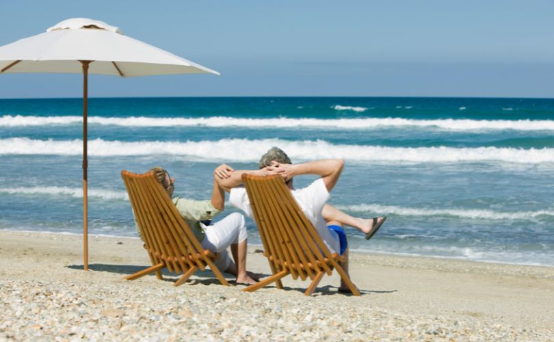Couple de retraités profitant de la plage sous un parasol, illustrant la douceur de vivre à l’île Maurice